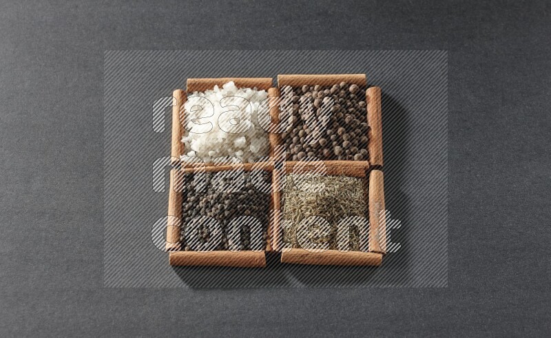 4 squares of cinnamon sticks full of black pepper, cumin, allspice and white salt on black flooring