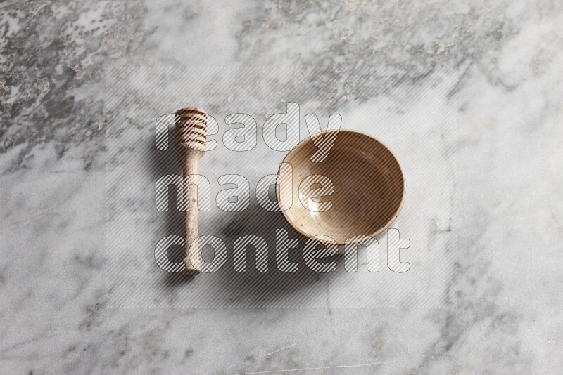 Beige pottery bowl with wooden honey dipper on the side on grey marble background