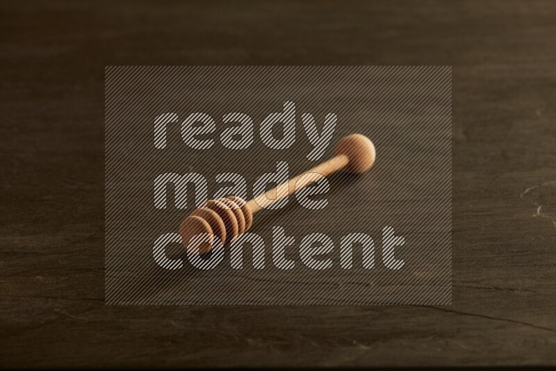 Wooden honey dipper on black slate background