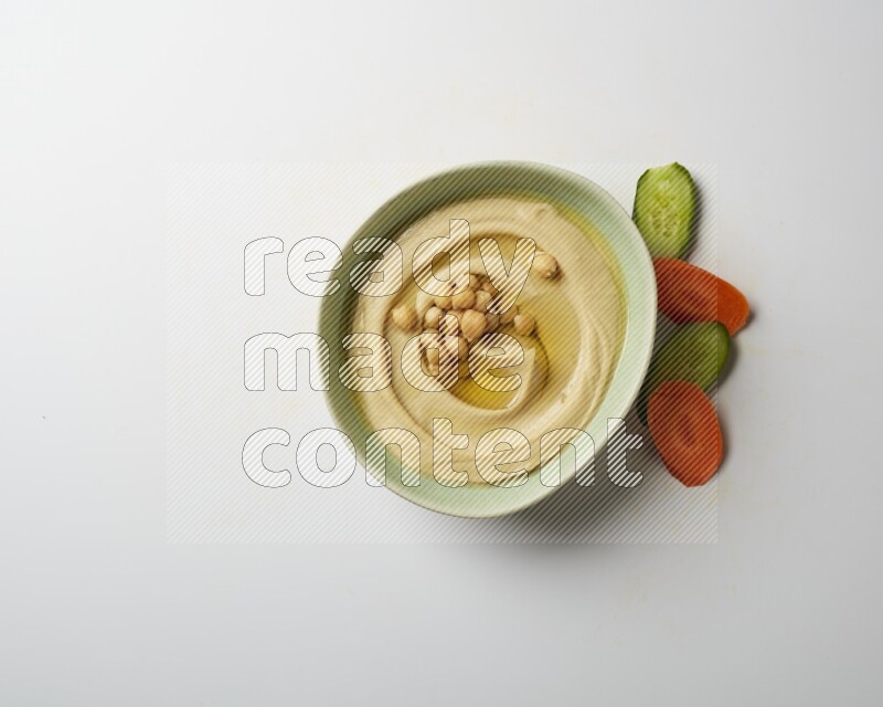 Hummus in a green plate garnished with roasted chickpeas  on a white background