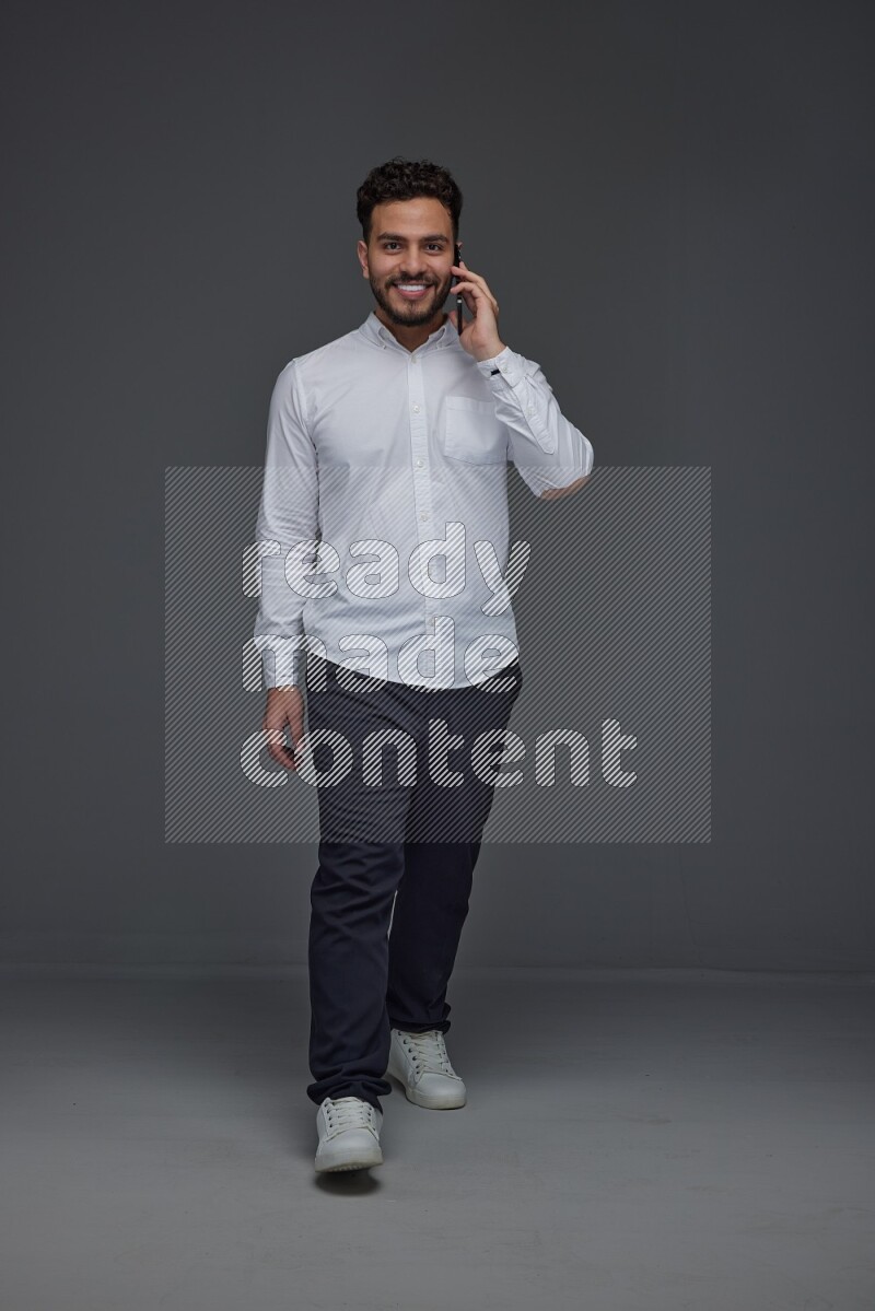 A man wearing smart casual talking in the phone eye level on a gray background