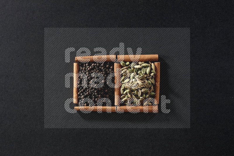 2 squares of cinnamon sticks full of black peppers and cardamom on black flooring