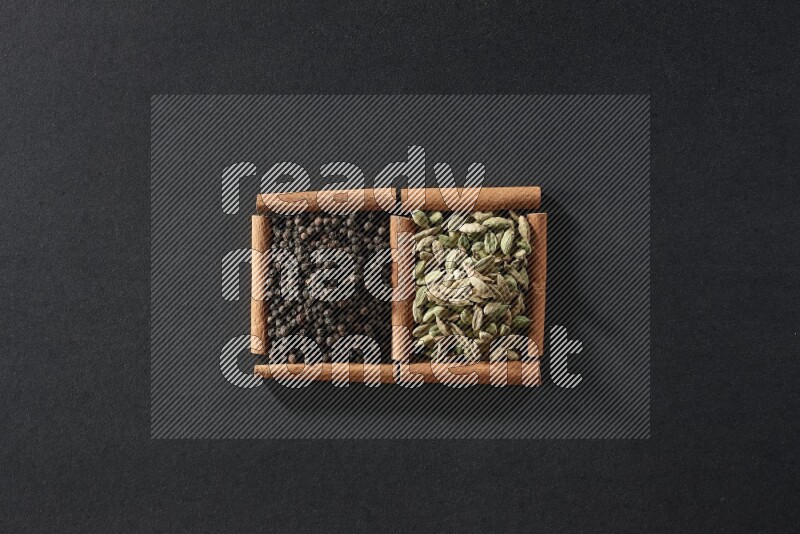 2 squares of cinnamon sticks full of black peppers and cardamom on black flooring