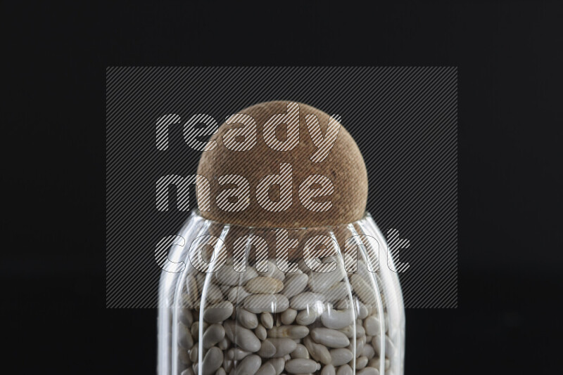White beans in a glass jar on black background