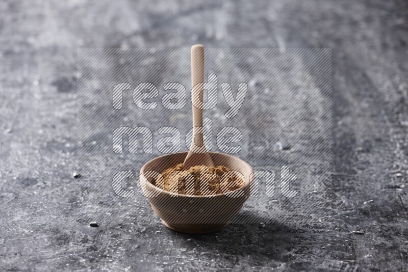 Wooden bowl full of cinnamon powder with a wooden spoon on a textured black background in different angles