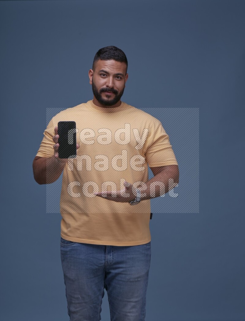 رجل يرتدي بنطال ازرق جينز وقميص اصفر بأكمام قصيره يشير الى جواله