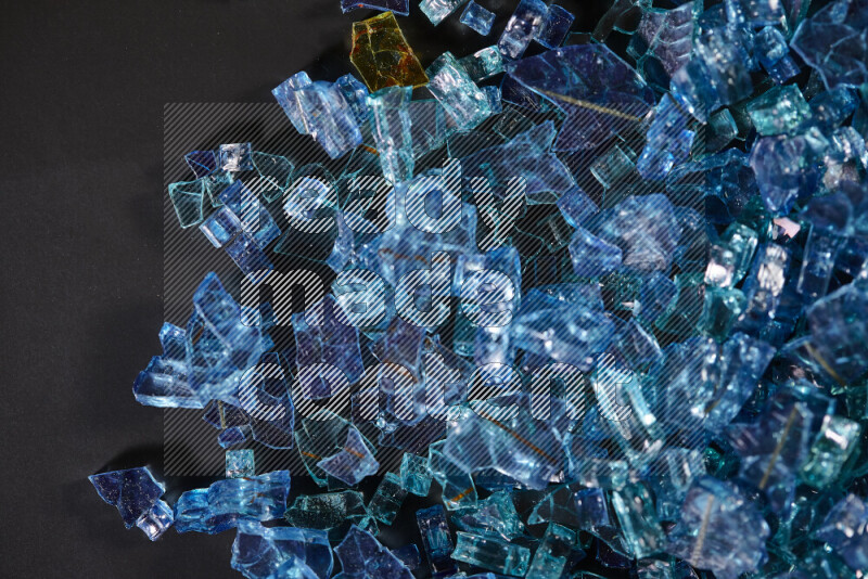Transparent blue fragments of glass scattered on a black background