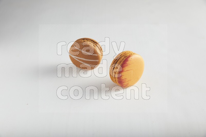 45º Shot of of two assorted Brown Irish Cream, and Orange Exotic macarons on white background