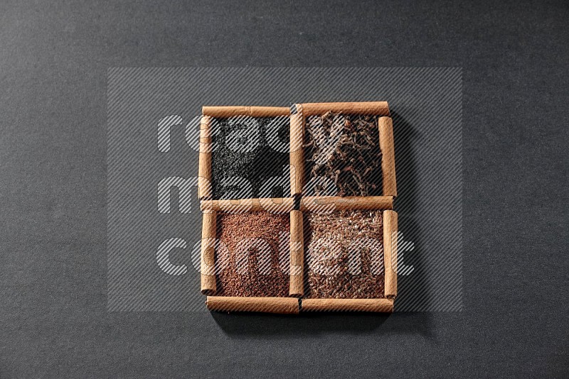 4 squares of cinnamon sticks full of black seeds, garden cress, flaxseeds and cloves on black flooring