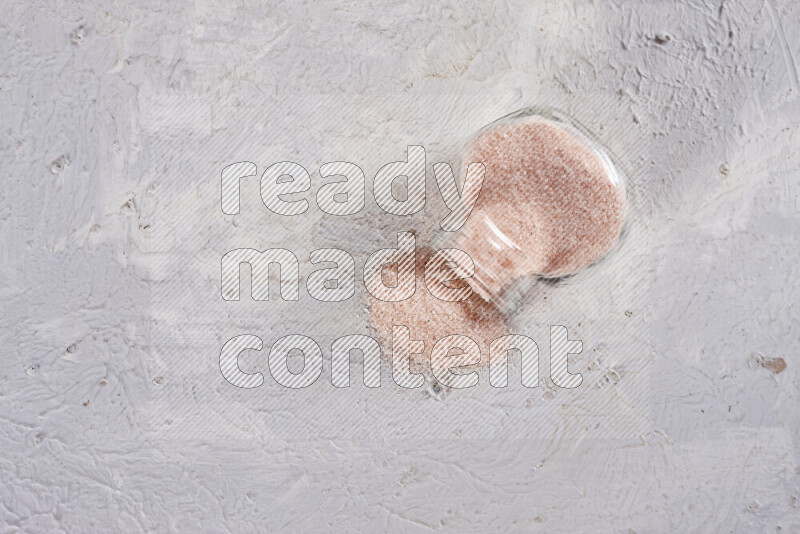 A glass jar full of fine himalayan salt on white background