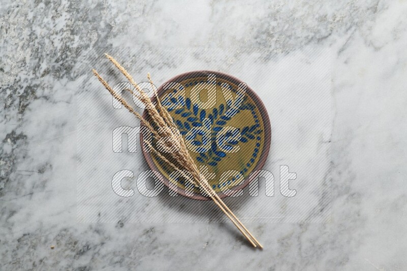 Wheat stalks on decorative pottery plate on grey marble background