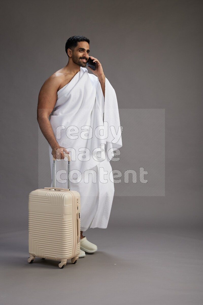 A man wearing Ehram Standing holding traveling bag on gray background