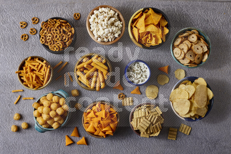 Assorted snacks in pottery bowls on grey background