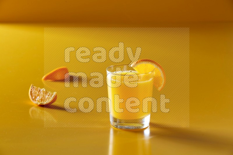 glass of orange juice with orange slice on yellow background