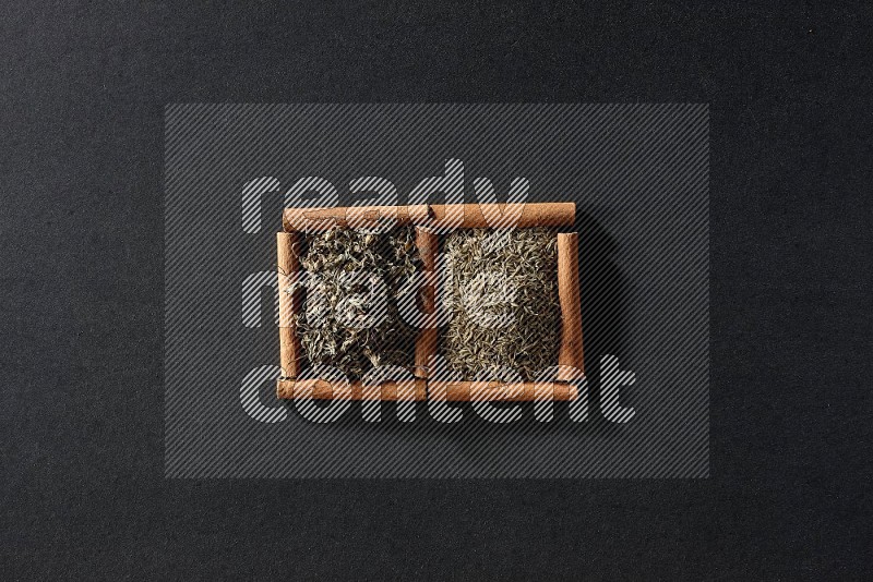 2 squares of cinnamon sticks full of cumin and dried basil on black flooring