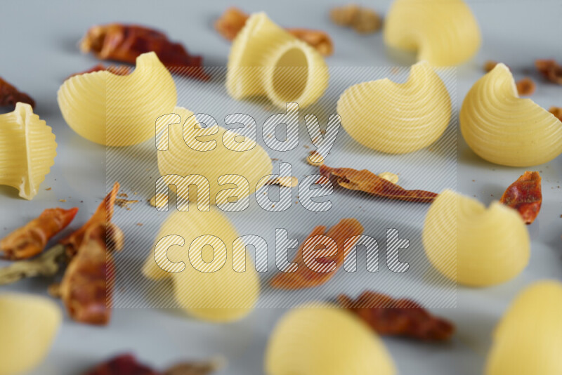 معكرونة مع مكونات متنوعة من الطماطم والثوم والبصل والفلفل الأحمر والفلفل الأسود والفلفل الأبيض وأوراق الغار وإكليل الجبل والهيل و مشروم على خلفية زرقاء فاتحة