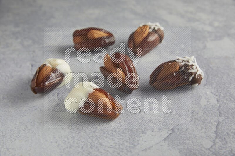 Group of Almonds stuffed dates plain and covered with chocolate on a light grey background