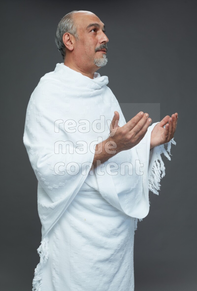 A man wearing Ehram Standing dua'a on gray background