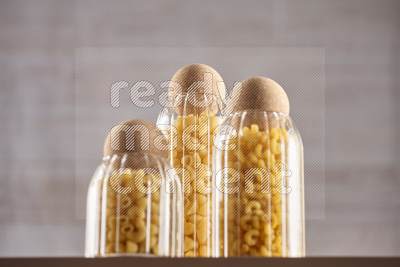 Raw pasta in glass jars on beige background