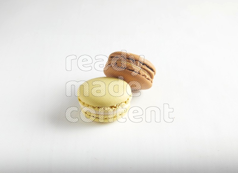45º Shot of of two assorted Brown Irish Cream, and Yellow Lime macarons on white background
