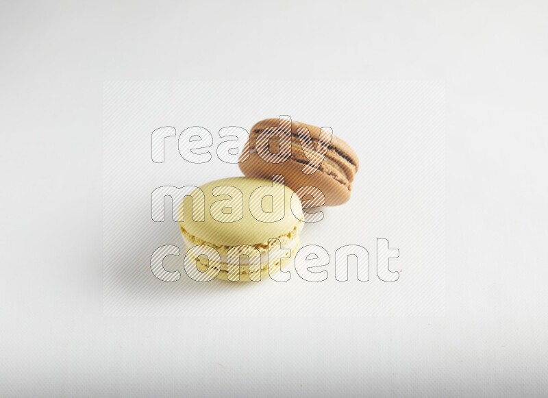 45º Shot of of two assorted Brown Irish Cream, and Yellow Lime macarons on white background