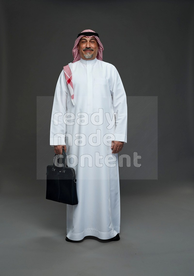 Saudi man with shomag Standing holding bag on gray background