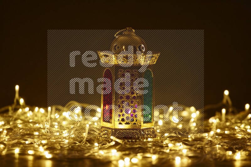 A traditional ramadan lantern surrounded by glowing fairy lights in a dark setup