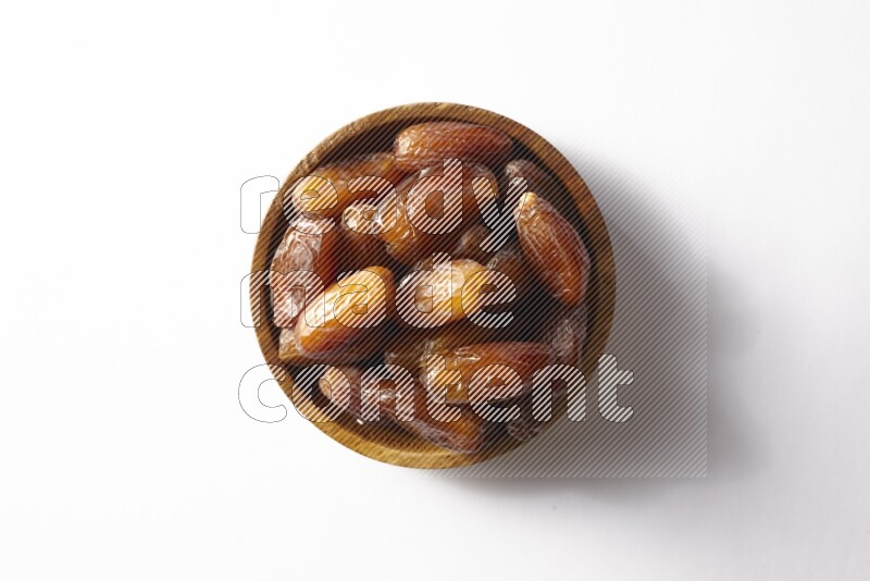 Dates in a wooden bowl on white background