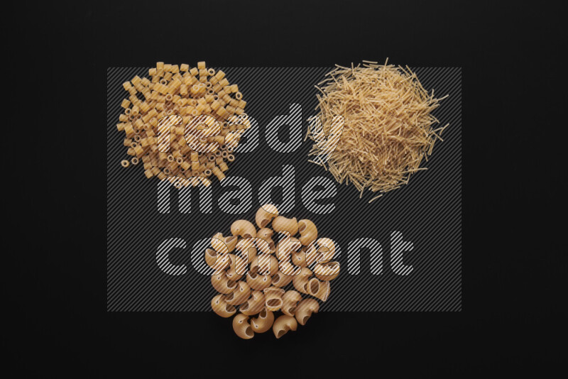 Different pasta types in bunches on black background