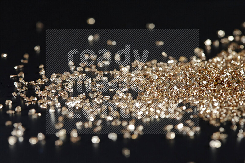 Gold shimmering fragments of glass scattered on a black background