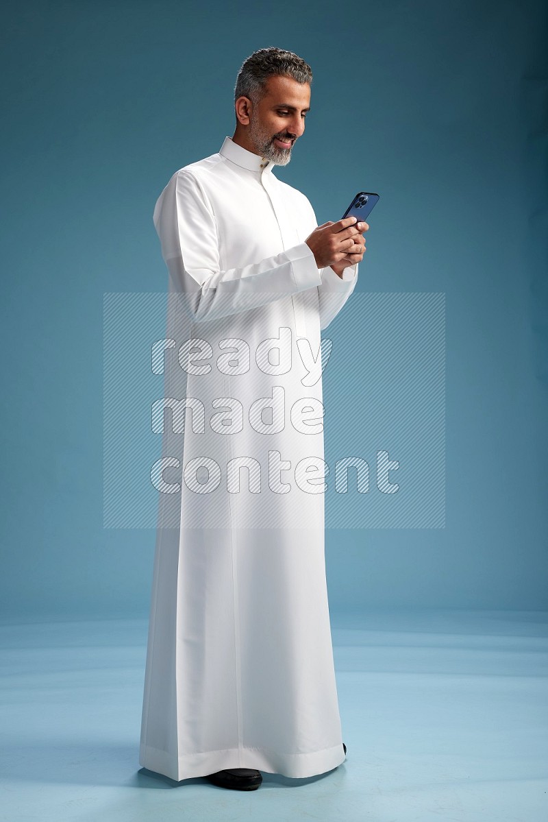 Saudi man waring thob texting on blue background