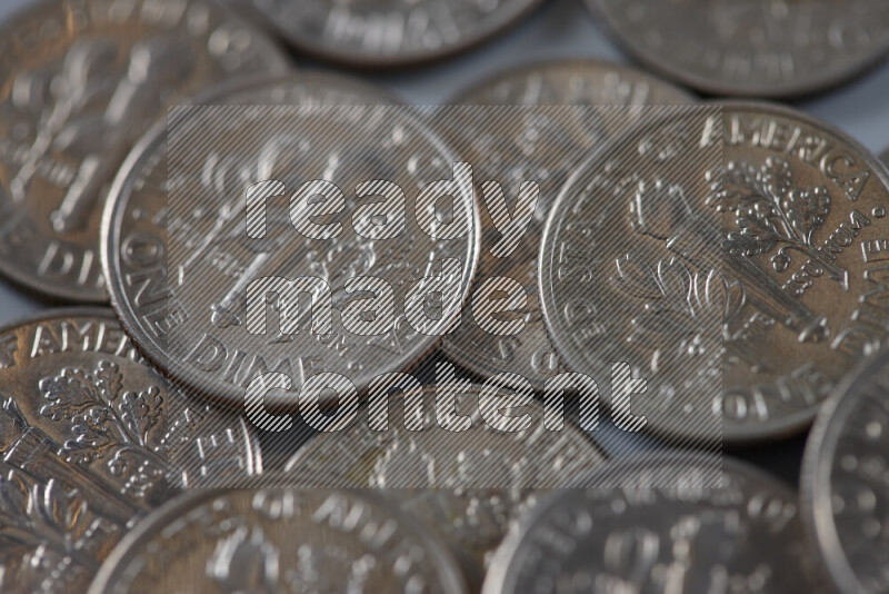 A close-up of scattered United States one dime coins on grey background