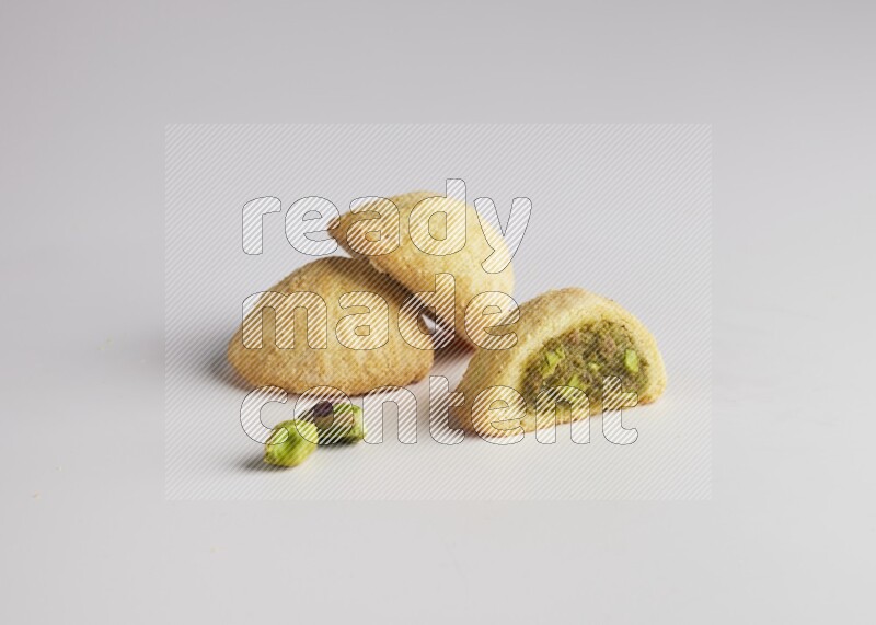 Three Pieces of Maamoul filled with pistachio paste  one of them is cut direct on white background