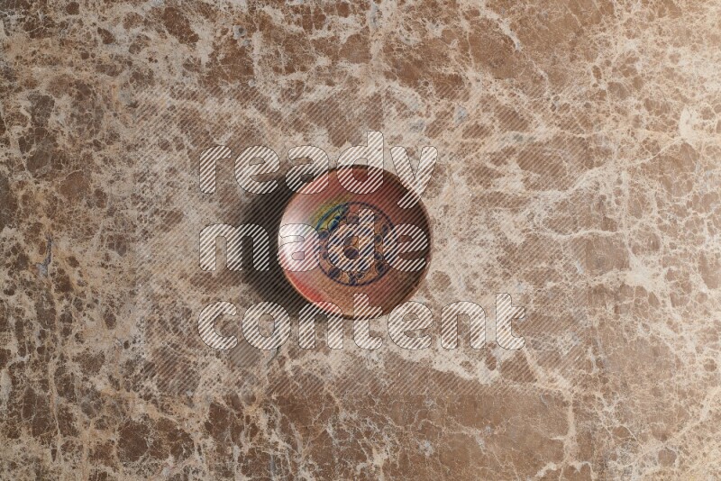 A decorative pottery plate on beige marble background