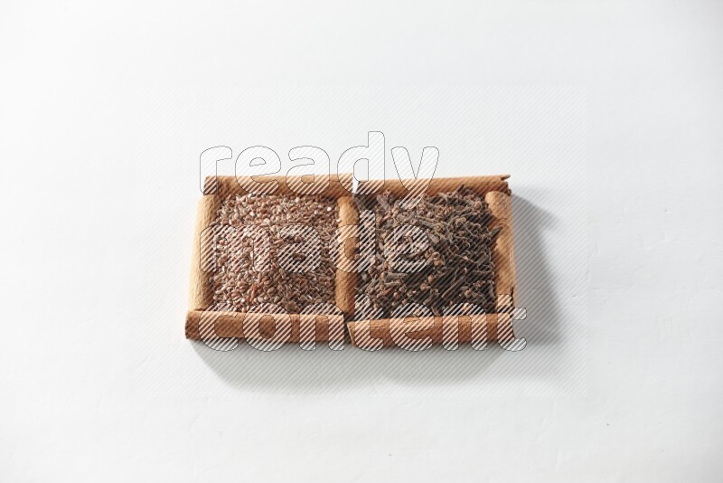 2 squares of cinnamon sticks full of cloves and flaxseeds on white flooring