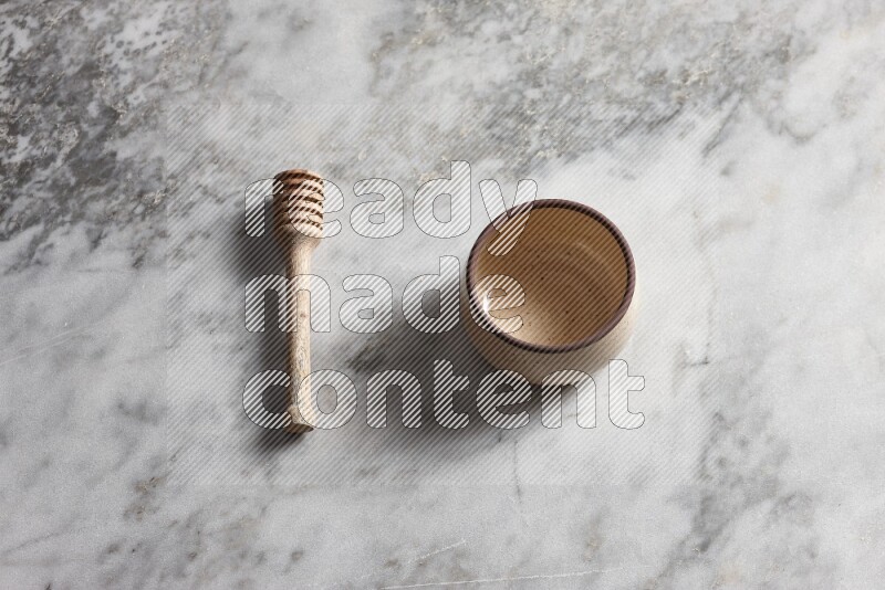 Beige pottery oven bowl with wooden honey dipper on the side on grey marble background