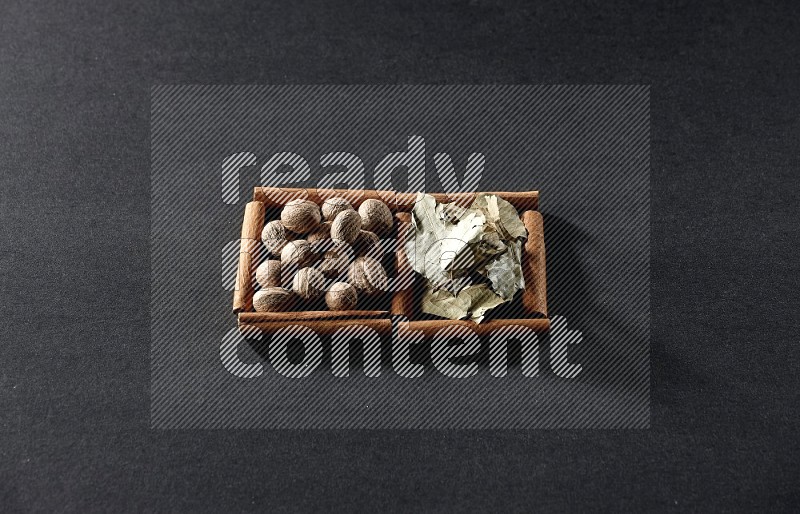 2 squares of cinnamon sticks full of nutmegs and bay laurel leaves on black flooring