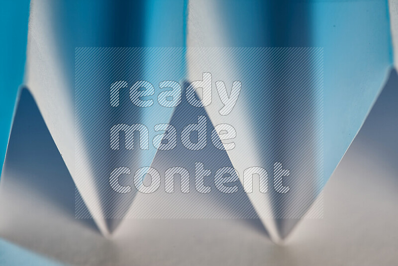 صورة مجردة مقربة تظهر طيات ورقية هندسية حادة بتدرجات اللون الأبيض و الأزرق