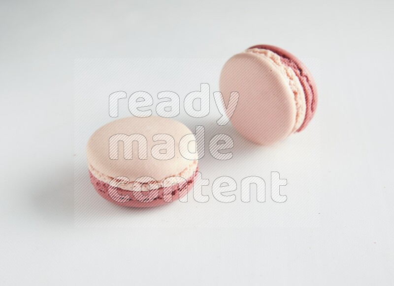 45º Shot of two Pink Litchi Raspberry macarons on white background