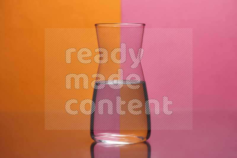 تظهر الصورة أواني زجاجية ممتلئة بالماء موضوعة على خلفية من اللونين البرتقالي والوردي