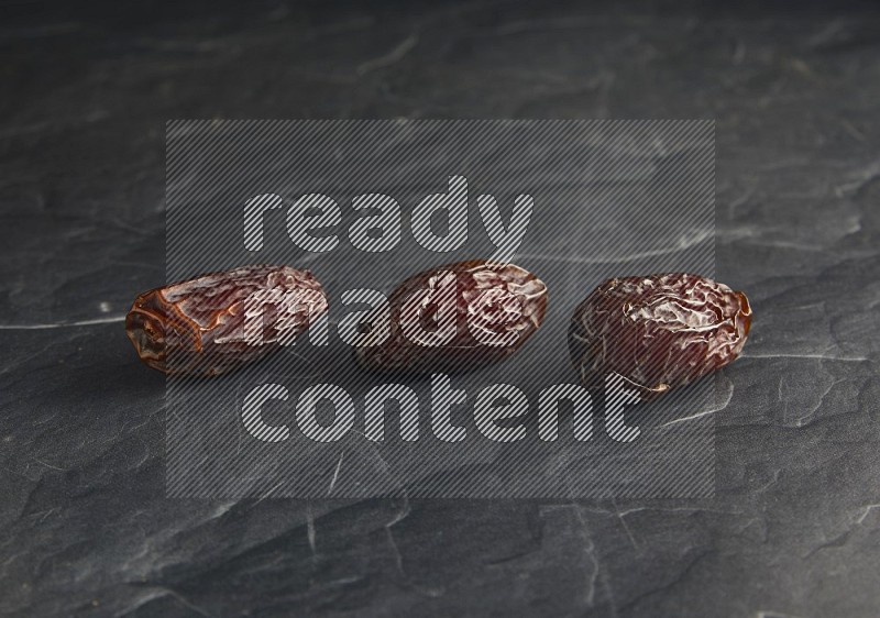 three madjoul dates on a black textured background