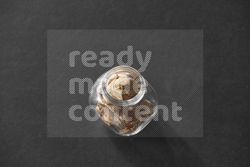 A glass spice jar full of ginger on black flooring