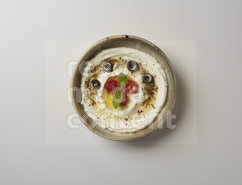 Lebnah garnished with cherry tomato, mint, olives & pine nuts in a grey pottery plate on a white background