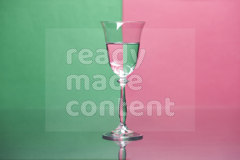 The image features a clear glassware filled with water, set against green and pink background