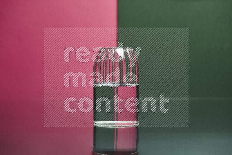 The image features a clear glassware filled with water, set against pink and dark green background