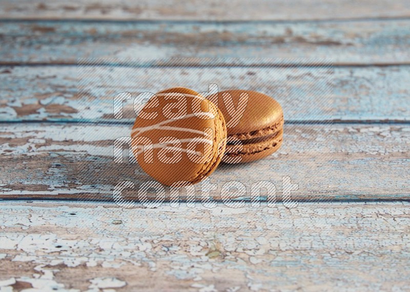 45º Shot of of two assorted Brown Irish Cream, and Brown Coffee macarons on light blue background
