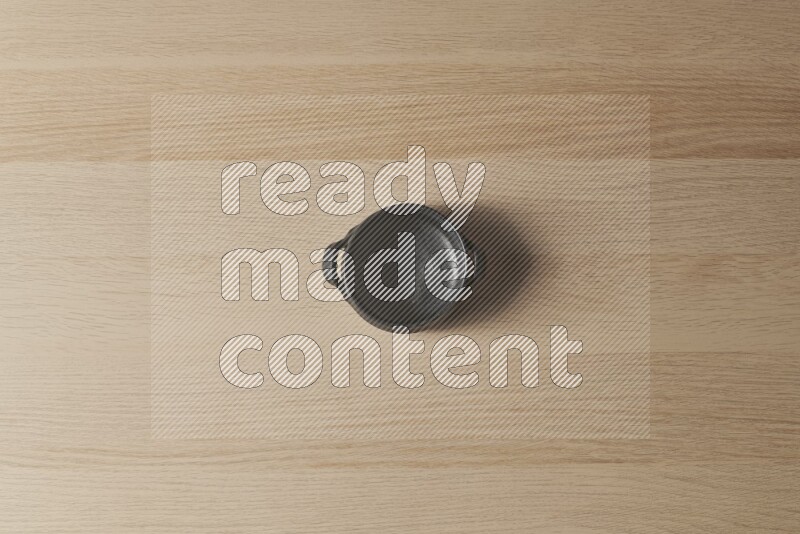 A black pottery bowl on light wooden background