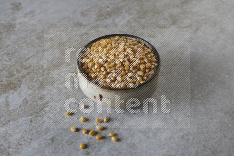 corn kernel in multi-colored pottery bowl on a grey textured countertop