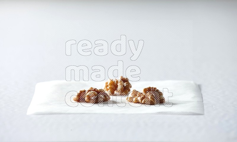 3 peeled walnuts on a piece of paper on a white background in different angles