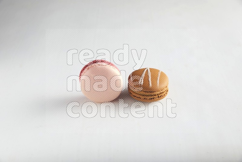 45º Shot of of two assorted Brown Irish Cream, and Pink Litchi Raspberry macarons on white background